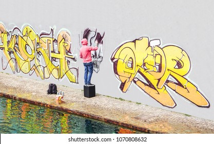 Street graffiti artist painting with a color spray can a graffiti on the wall in the city - Concept of contemporary art lifestyle
