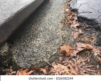 Street Gutter, Storm Water Drainage System Surrounded By Leaves And Crumbling Asphalt Street Surface