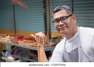 Street Hawker Man Working Pointing Thumb Up To Delicious Meatball Skewer Street Food; Concept Of Asian Street Food, Tourism With Local Food, Small Business, Street Food Hawker