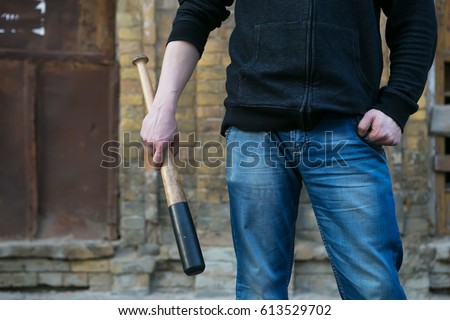Street hooligan is holding a baseball bat.