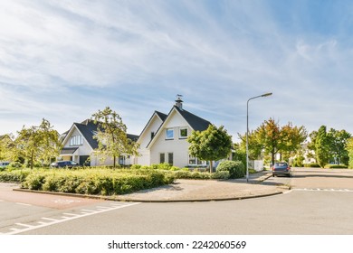 a street with houses and cars parked in the parking lot on either side of the road there is a blue sky filled with white