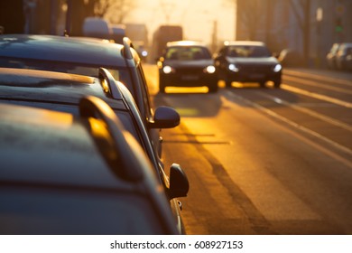 Street Inside City, Morning Twilight With Parking Cars, Two Further Blurred With Illuminated Headlights On The Road, One Pass The Other (copy Space)/Car Overtake Street Scene