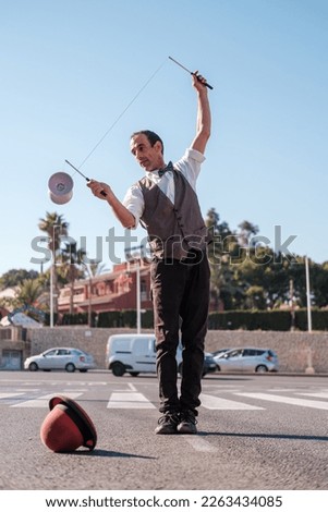 street juggler in bow tie and waistcoat juggles with a diabolo
