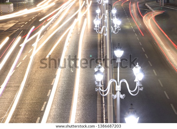 Street lamp in the night with abstract of movement\
car light on the road.