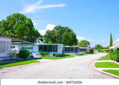Street level view of a very well kept mobile home trailer park neighborhood in central Florida with nice yards and big green trees on a beautiful sunny afternoon