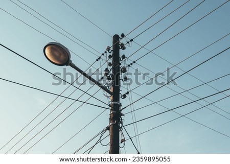 Street light with electricity utility pole and electrical wires, low angle view
