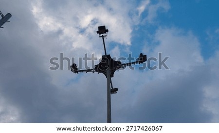 Street lighting pole with multiple LED floodlights against dramatic cloudy blue sky. Urban infrastructure, public lighting system, outdoor technology, city safety and illumination concept