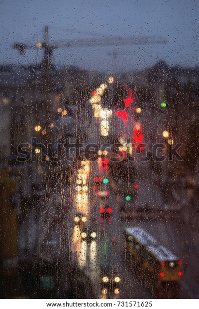 Street lights behind a window.  Traffic in the\
city of Berlin in a rainy\
night.