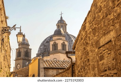 A street of a medieval Italian town with tiled roofs, lanterns and a basilica dome - Shutterstock ID 2275192003