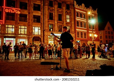 Street Music Performance. Man With Guitar Singing Songs At Night City Street Before People. Wroclaw, Poland - August 14, 2021