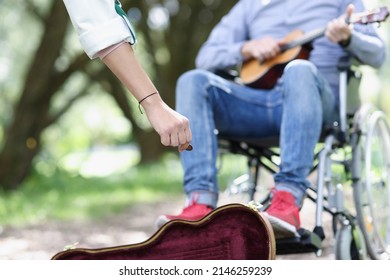 Street Musician With Guitar In Wheelchair Makes Money. Disabled Person And Poverty And Earnings Concept