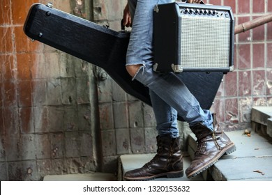 Street musician holding a case with a guitar and amplifier. Vagrant lifestyle. Playing to make money a living. Unemployed musician. Future rock star. Horizontally framed shot. - Powered by Shutterstock