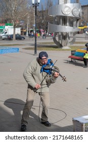 Street Musician On The Electronic Violin. A Mature Man Wearing A Black Baseball Cap With An Audi Logo. Ukraine, Nikolaev - 02 19 2022