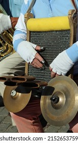 Street Musician on the road playing the musical Instrument with cymbals and a special grater and thimbles on the hand