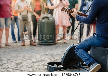 Street musician playing guitar on city street in summer