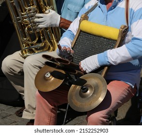 Street Musician playing the musical Instrument with metal cymbals and a special grater on the road