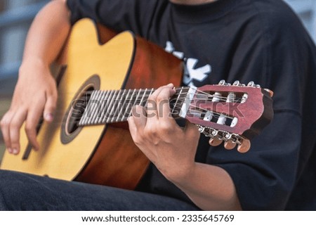 A street musician plays the guitar. Close-up of hands plucking chords. Guitar neck