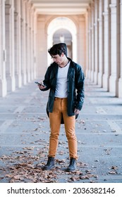 Street Musician Walking In The Street With Guitar Case. Young Handsom Man Using Smartphone Outdoors