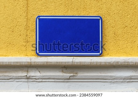 Street name sign plate, blue metallic plate on old yellow wall, mockup copy space and design element