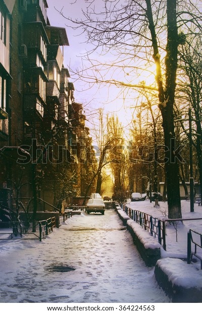 Street with\
the old car in the winter sunset,\
snow.