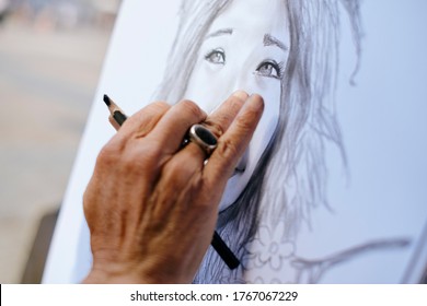Street Painter Drawing Portrait Of Tourist With Charcoal