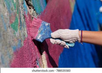 The Street Painter Paints The Retaining Wall With A Brush