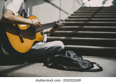 Street performer plays guitar .  Young street musician playing guitar and busking for money