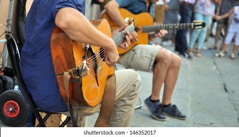 street performers with guitar, with audience in the background