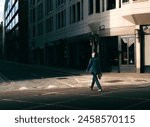 Street Photo of Man Walking Across the Road in Shaft of Golden Sunlight and Dark Shadows in London, UK