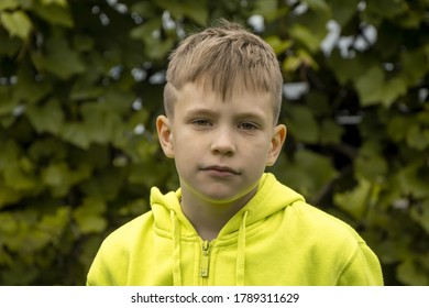 Street Portrait Of A 10-year-old Boy With A Serious Face And A Fashionable Haircut Against The Background Of Nature. Concept: Soon To School, Summer Vacation In The Country,