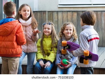 Street portrait of friendly happy junior school girls and boys talking