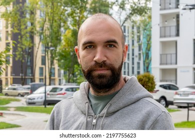 Street Portrait Of A Serious Man 30-35 Years Old With A Beard On The Background Of Beautiful High - Rise  Buildings.