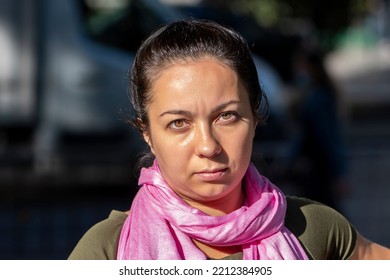 Street Portrait Of A Serious Woman 35-40 Years Old With A Pink Scarf Around Her Neck On A Neutral City Background, Sunny Day, Summer Weather.