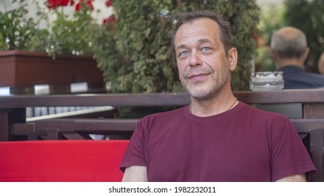 Street Portrait Of A Smiling Man 45-50 Years Old In An Open Summer Cafe, Recreation And Tourism.