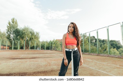 Street portrait of a stylish lady in roe deer stands on a basketball court and poses for the camera. Attractive Hispanic girl posing in street location.
