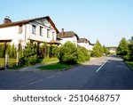 Street in residential area in suburb. Rows of houses along road, sidewalk. Family house outside city. Dream country home. Home outside the city. Road at village. Trees and green lawn at Villa.