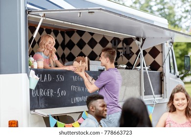 street sale and people concept - happy young saleswoman at food truck serving male customer - Powered by Shutterstock