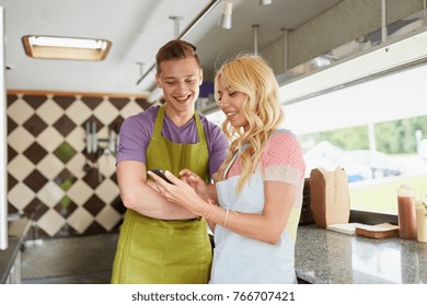 street sale, technology and people concept - happy couple of young sellers with smartphone at food truck - Powered by Shutterstock