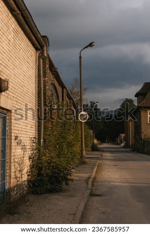 A street scene featuring a reflective traffic mirror hanging from the side of a derelict brick building