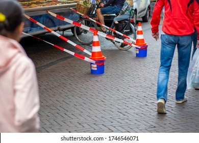 Street Scene Social Distancing Safety Measures On The Local Food Market During Coronavirus Covid-19. People Can Wait Separated In Queue. Pawns With Caution Tape Indicates The Safe Social Distance.