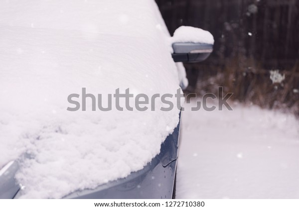 In the street side parked cars covered\
with snow. Car under snow and ice in\
winter.