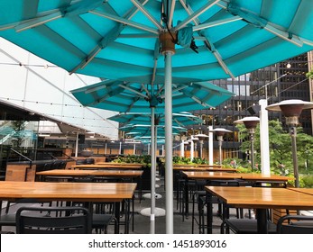 A Street Side Patio Of A Restaurant Bar Cafe, With Wooden Tables, Large Turquoise Umbrellas, Outdoor Heaters, Waiting For Patrons On A Beautiful Sunny Summer Day In Downtown Toronto.