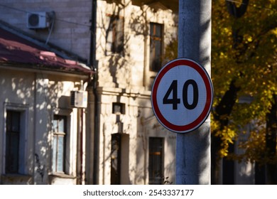 A street sign with the number 40 on it hangs on a pole, the sign indicates the speed limit. The sign is surrounded by shadows and the street is empty. - Powered by Shutterstock