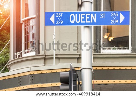 Street sign of Queen Street in Auckland - Urban concept and road direction in the biggest city of New Zealand - Australasian world famous destination with warm filter and enhanced sunshine halo