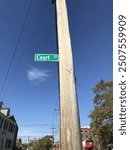 A street sign reading "Court ST" mounted on a weathered wooden pole against a clear blue sky