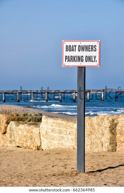A street sign in Swakopmund\
Namibia Southern Africa at the Atlantic Ocean against a blue sky\
and the jetty in the background saying boat owners parking\
only