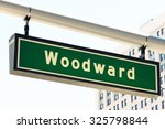 Street sign for Woodward Avenue, a main thoroughfare in the City of Detroit, Michigan.  This is where the annual "Dream Cruise" is held.  There is a generic office building in the background.