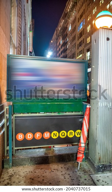 Street signs and public transit directions of New\
York City subway at\
night..