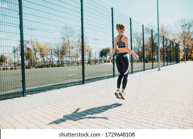 Street sport. The girl jumps on a skipping rope. Athletic girl in a sports uniform. - Powered by Shutterstock