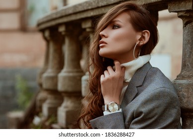 Street style autumn portrait of elegant fashionable woman wearing trendy silver wrist watch, checkered blazer, white turtleneck, hoop earrings, posing outdoors, in city. Copy, empty space for text